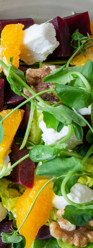 Photo of salad with walnuts, beets, arugula, small cubes of white cheese, and mandarin orange bits